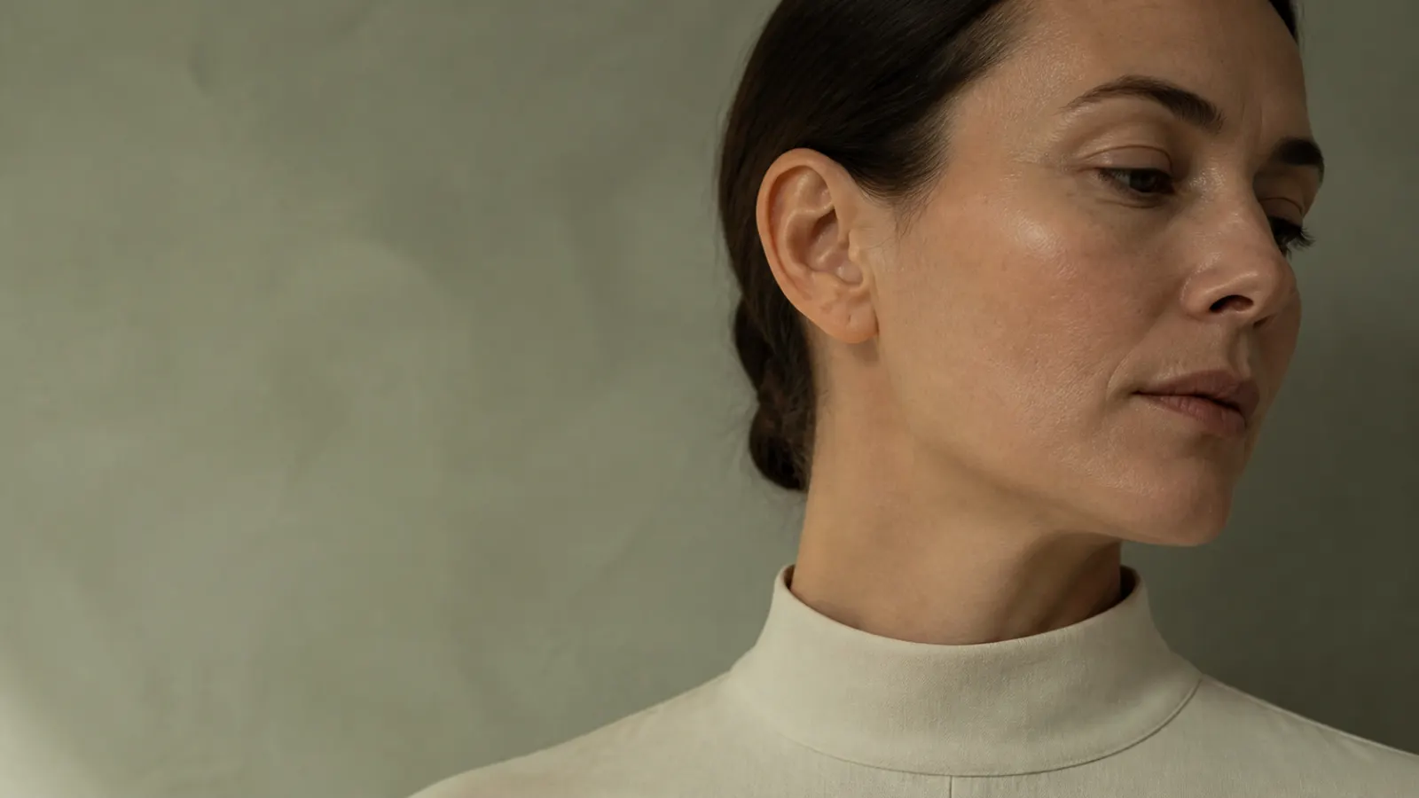 Adult woman resting in soft sage-toned natural light.