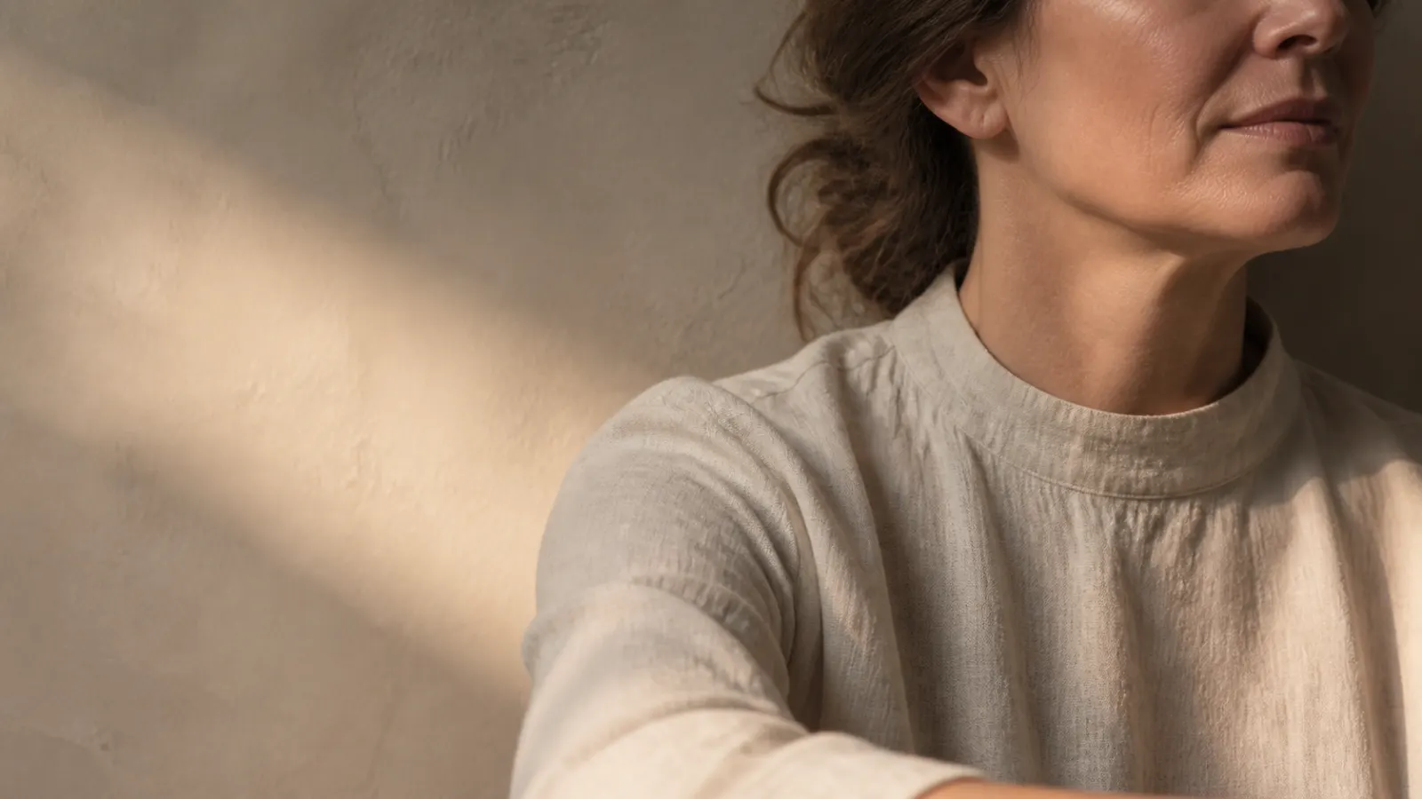 Adult woman resting in warm natural light with soft botanical shadows.